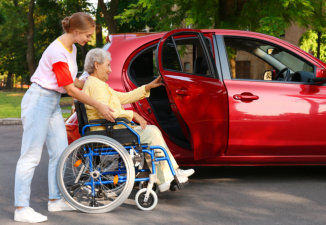 young woman helping a senior get in a car